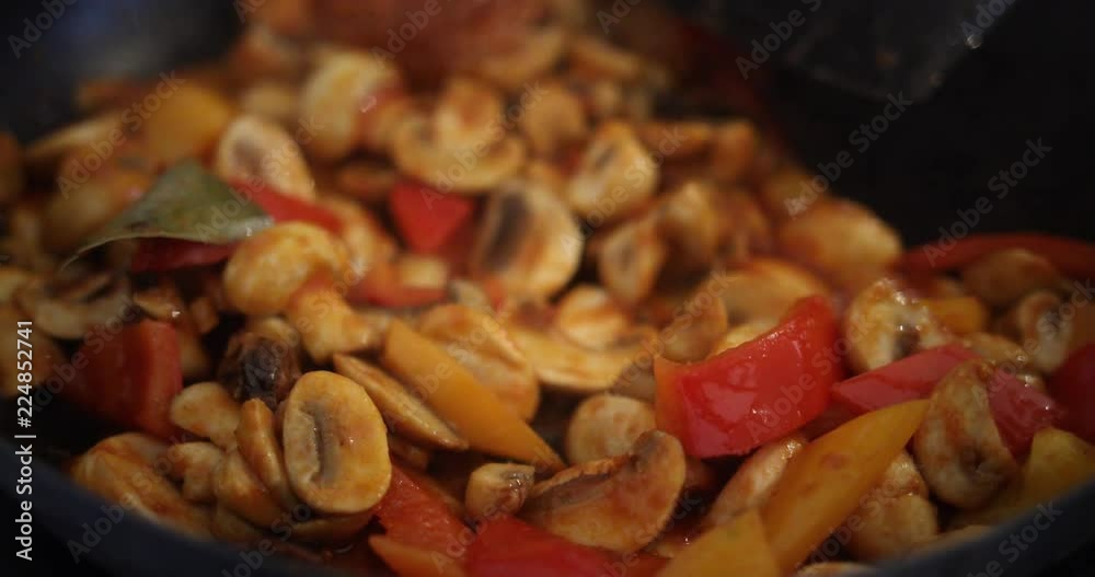 Pouring sauce over a vegetarian curry with mushrooms and peppers in a frying pan. Pouring sauce over a vegetarian curry with mushrooms and peppers in a frying pan.