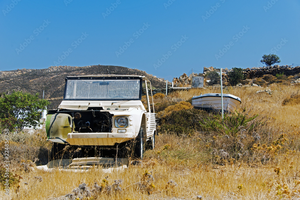 A view of a wrecked car and a boat in the land of Patmos, Greece in summer