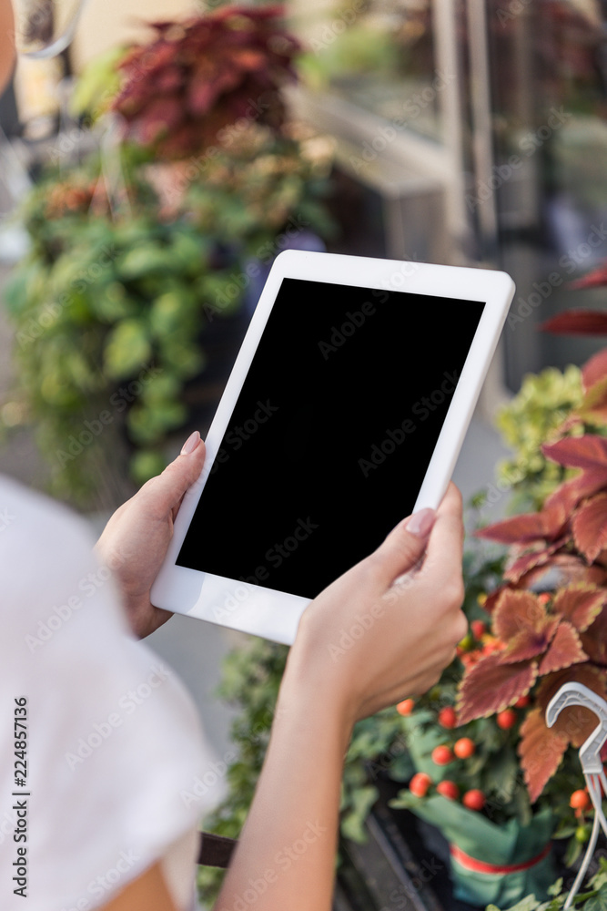 cropped image of florist holding tablet with blank screen near flower shop