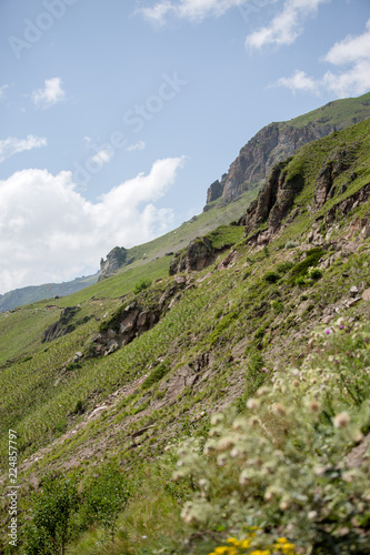 Photo of mountain slopes with vegetation and cloudy sky