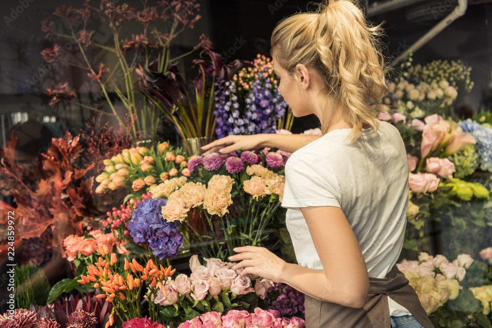 © LIGHTFIELD STUDIOS - back view of florist taking care of bouquets in flower shop