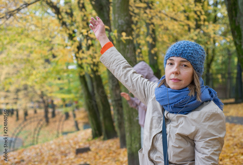 Young woman in hat and headphones dancing in autumn park