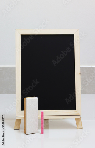 empty blackboard and colored chalks and brush removes the board on floor background