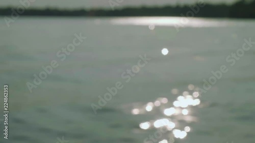 Defocused sparkles of sunlight on water surface during sunset photo