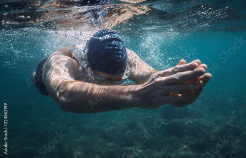 Underwater view of swimming man. Male athlete swimming in the sea photo