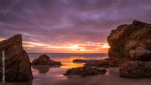 Cloudy colourful sunrise over rocky beach