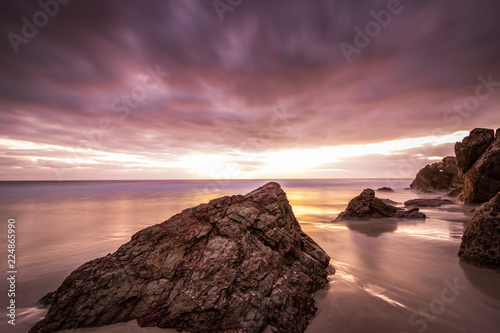 Cloudy colourful sunrise over rocky beach