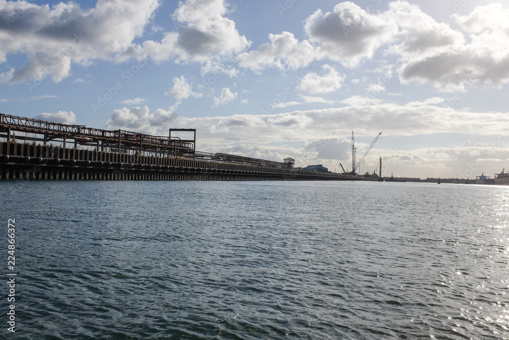 Ship loading dock on harbour beneath cloudy sky Ship loading dock on harbour beneath cloudy sky