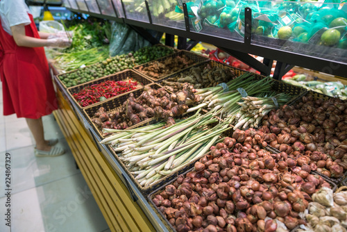 Vegetables on shelves in supermarket with fresh chilli, dry onion, dry ginger, dry citronella...