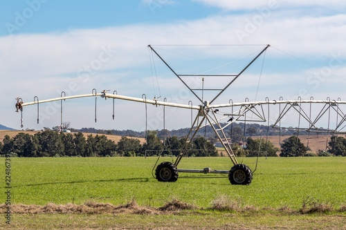 Travelling irrigator on farmland against cloudy blue sky photo