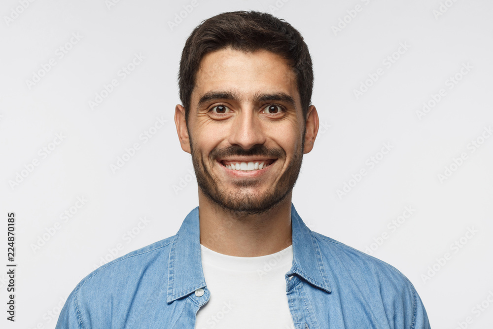 Close up portrait of young smiling handsome student in blue denim shirt isolated on gray background