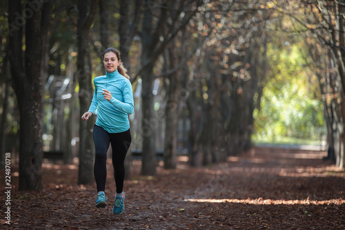  A beautiful girl in sportswear is running around in the park in the fall.