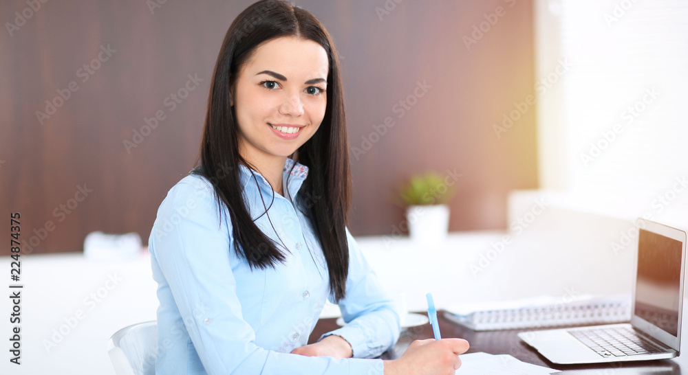 Young brunette business woman looks like a student girl working in office. Hispanic or latin american girl happy at work and too busy Young brunette business woman looks like a student girl working in office. Hispanic or latin american girl happy at work and too busy