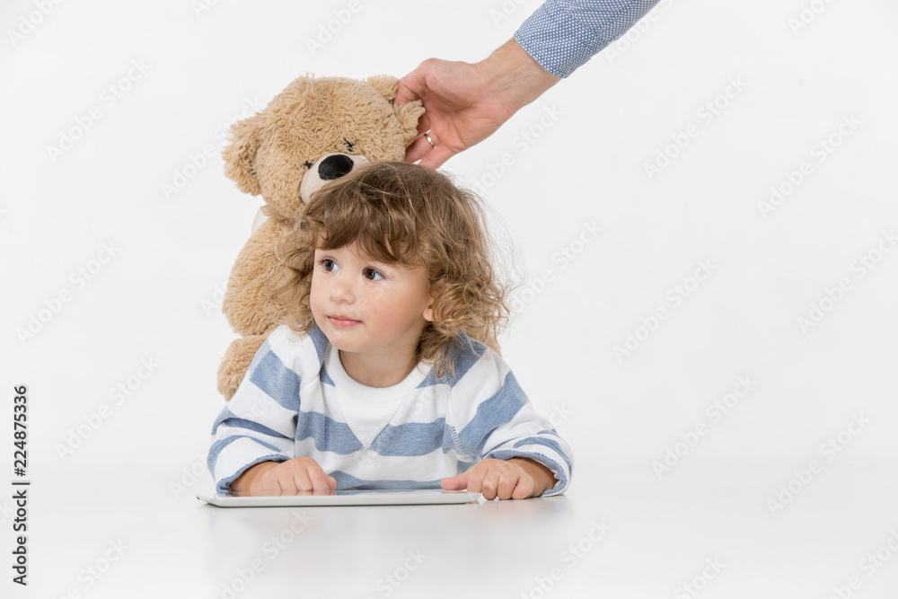 Portrait of happy joyful beautiful little boy sitting with laptop and teddy bear toy , studio shot on white Portrait of happy joyful beautiful little boy sitting with laptop and teddy bear toy , studio shot on white