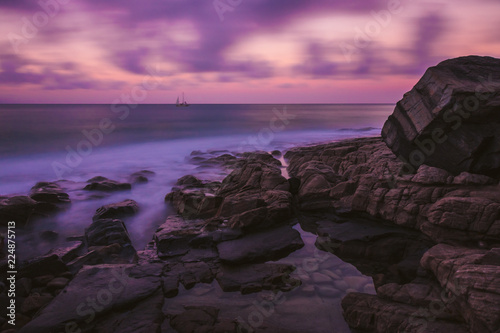 Cliff on shore of ocean in sunset