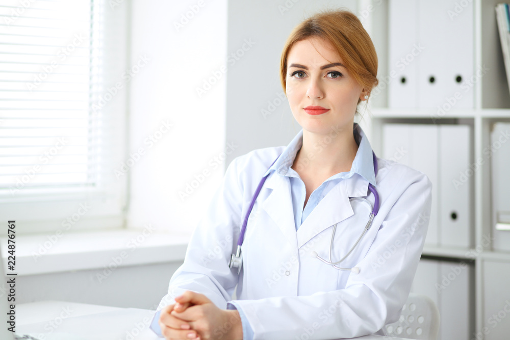 Female doctor sitting at the desk near window Female doctor sitting at the desk near window