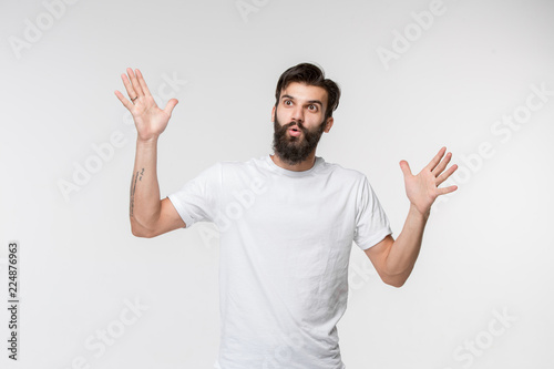 Wow. Attractive male half-length front portrait on white studio backgroud. Young emotional surprised bearded man standing with open mouth. Human emotions, facial expression concept. Trendy colors