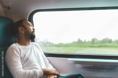 Portrait of a pensieve man on train looking outside of the window, traveling