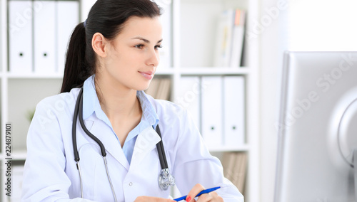 Young brunette female doctor at working place in hospital. Health care, insurance and help concept