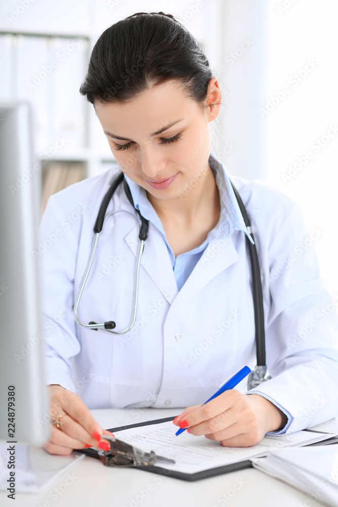 Young brunette female doctor at working place in hospital. Health care, insurance and help concept Young brunette female doctor at working place in hospital. Health care, insurance and help concept