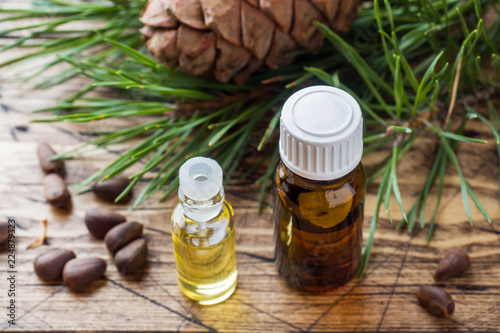 Cedar and spruce essential oil in small glass bottles on wooden background. Selective focus.