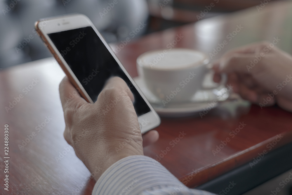 Closeup image of businessmen hands holding mobile with blank copy space screen for your text message or promotional content against desktop and cup of cool tea. Closeup image of businessmen hands holding mobile with blank copy space screen for your text message or promotional content against desktop and cup of cool tea.