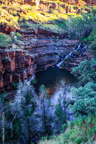 Waterfall and gorge surrounded by red rock cliff photo