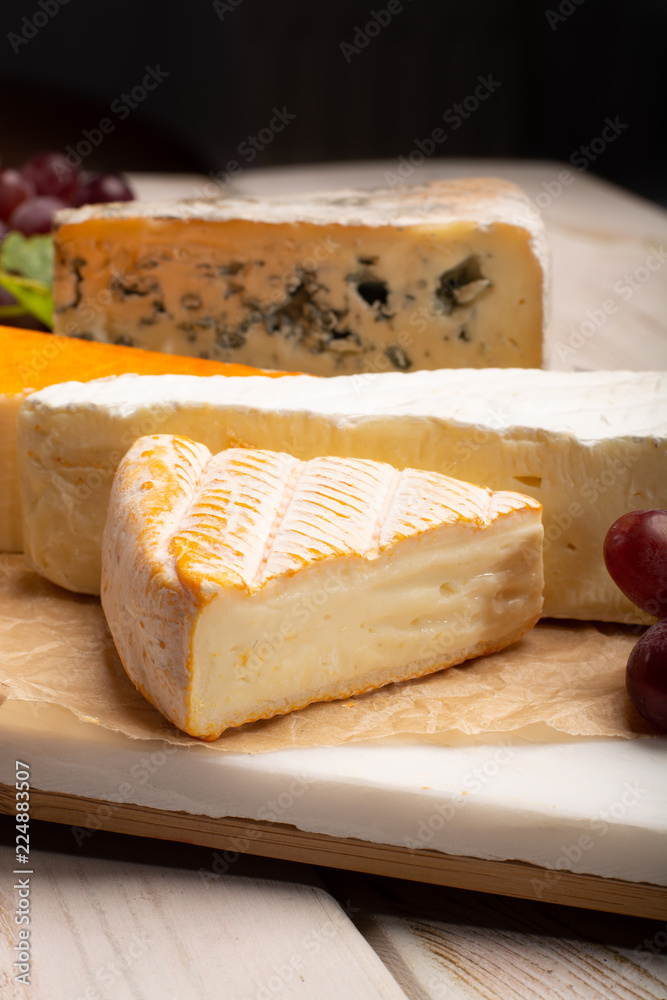 Tasting plate with four France cheeses, cream brie, marcaire, saint paulin  and blue auvergne cheese, served with fresh ripe grapes Stock Photo | Adobe  Stock