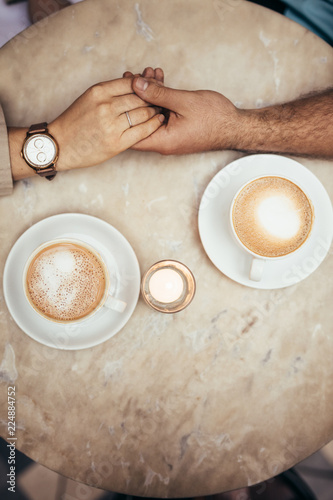 Hands of couple together on a coffee table