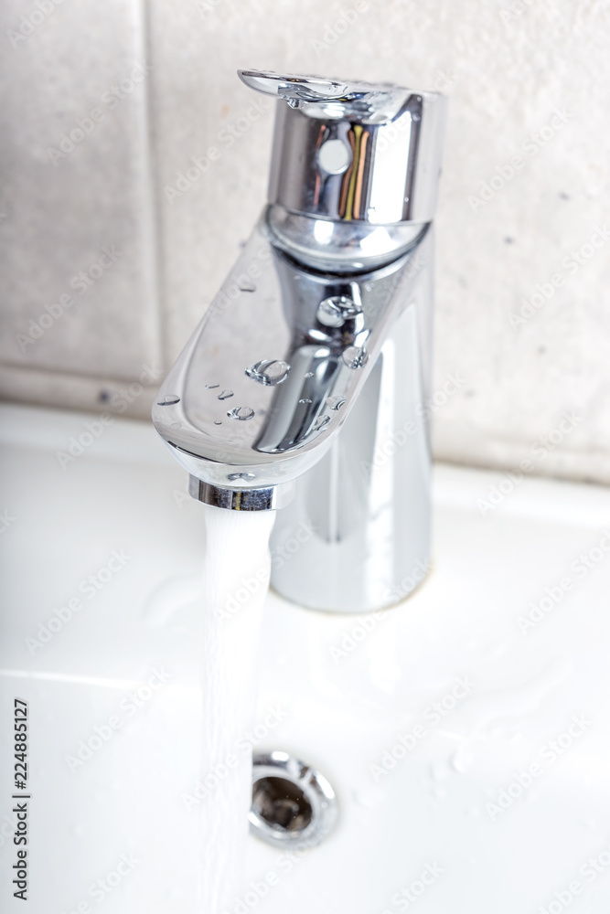 Flowing water from a modern designer chrome water tap Flowing water from a modern designer chrome water tap