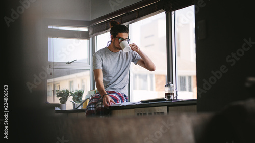 Man drinking coffee while reading a book