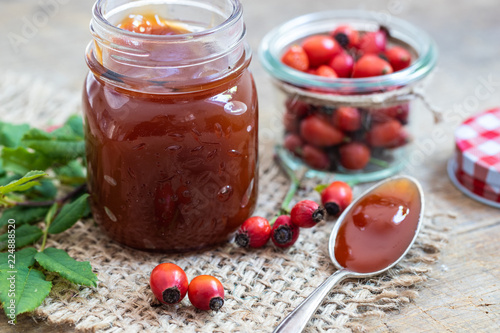 Marmeladenglas mit einem Löffel Hagebutten Marmelade
