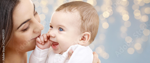 family and motherhood concept - happy smiling young mother with little baby over festive lights background © Syda Productions