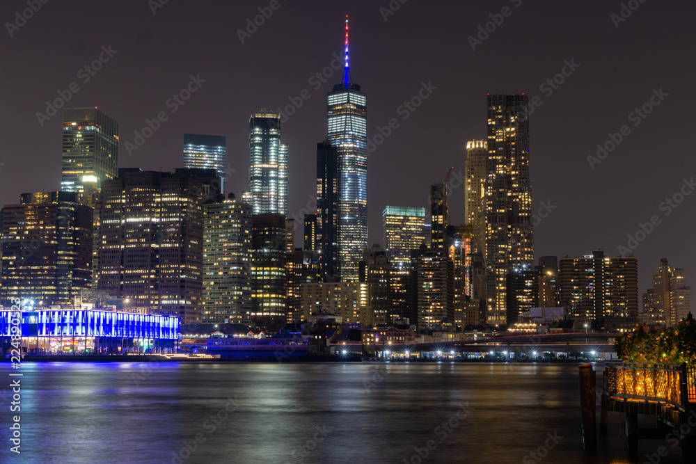 Long time exposure of New York City Manhattan downtown skyline at night viewed from Brooklyn Bridge park