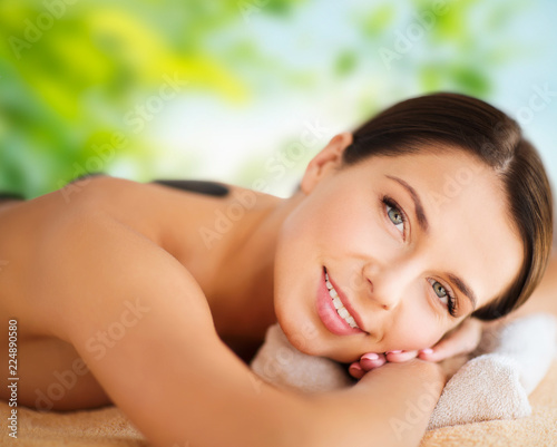 wellness  spa and beauty concept - close up of beautiful woman having hot stone therapy over green natural background