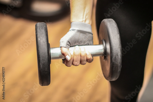 A girl in a gym doing her workout holding a lifting weight.