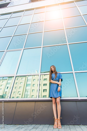 Fashion urban portrait of beautiful model on the street. Young slim woman wearing blue dress in the city