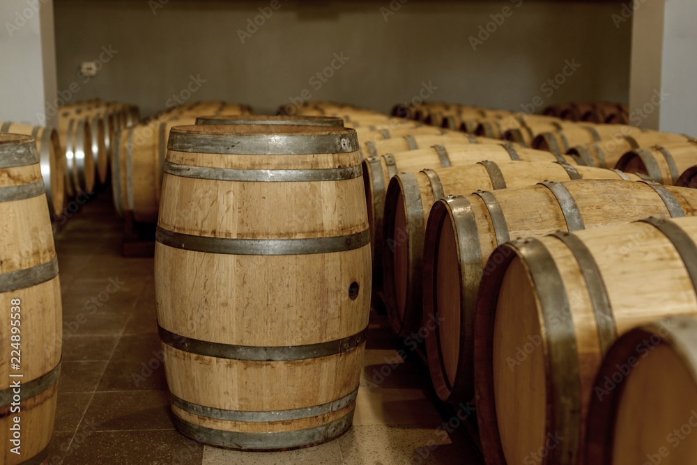 Wine oak barrels in which red wine is aged in the cellar of the winery. Concept of the production of wine Wine oak barrels in which red wine is aged in the cellar of the winery. Concept of the production of wine