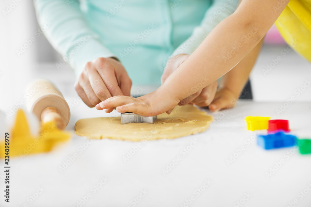 family, cooking and people concept - mother and little daughter with molds making cookies from dough at home kitchen family, cooking and people concept - mother and little daughter with molds making cookies from dough at home kitchen