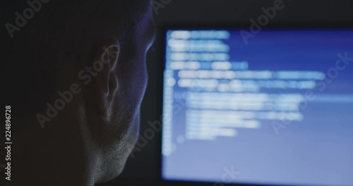 IT Programmer man typing in program code. Developer at work overtime. Hacker hacking late at night.