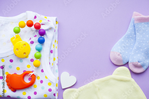 Baby yellow booties. Children's shoes and toys on purple background. Newborn. © 976photo