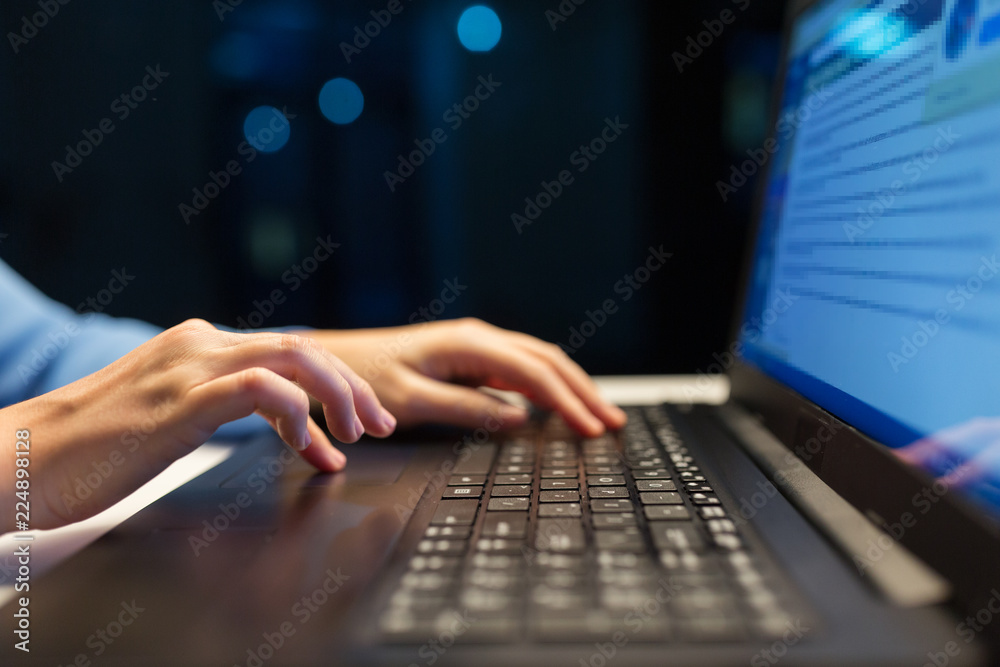 business, education and technology concept - close up of female hands with laptop typing at night