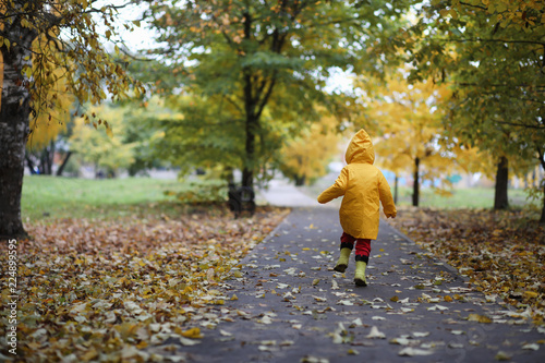 A child in a raincoat for a walk outside © alexkich