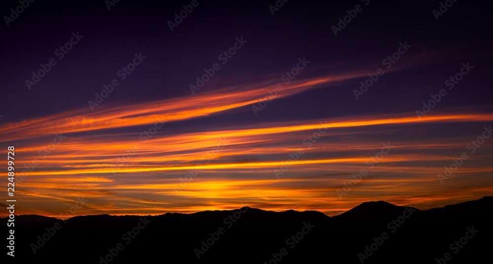Beautiful autumn sunset landscape with a lot of colors like red, purple, orange, yellow, blue... and the mountains silhouettes