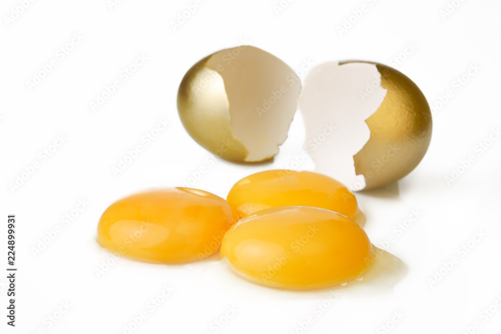 Broken golden egg and three yolks