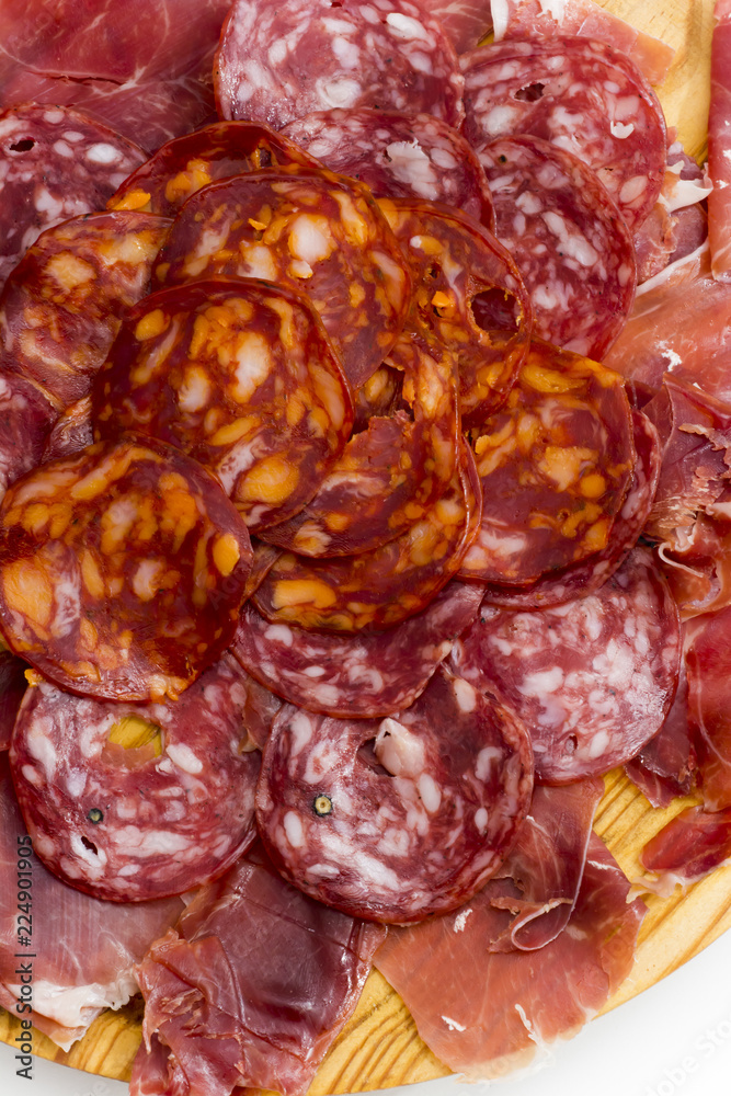 Typical spanish food with ham and sausage on a wooden plate Typical spanish food with ham and sausage on a wooden plate