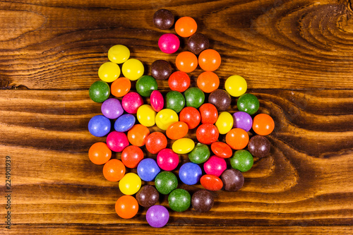 Pile of the multicolored candies on a wooden table. Top view