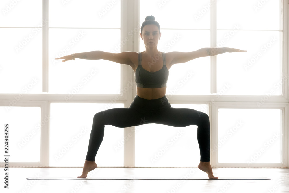 Young sporty attractive woman practicing yoga, doing Sumo Squat exercise,  Goddess pose, working out, wearing sportswear, grey pants, top, indoor full  length, at yoga studio Stock Photo | Adobe Stock
