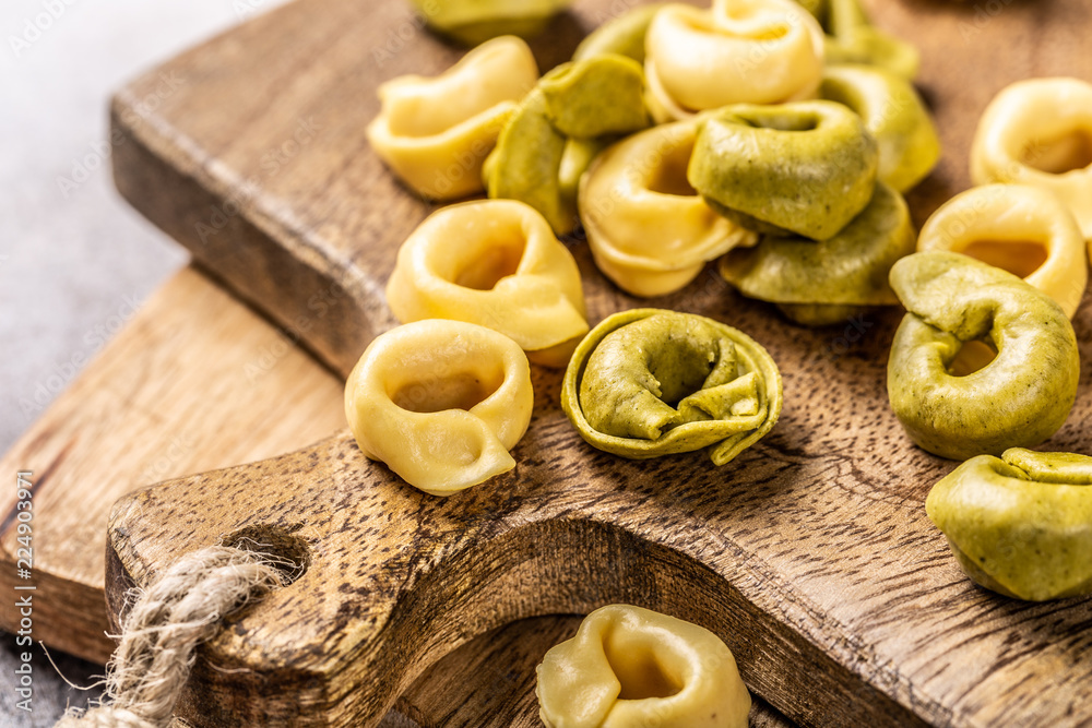 Homemade Tortellini with spinach, cheese and ricotta on wooden board. Gluten free italian food concept. Homemade Tortellini with spinach, cheese and ricotta on wooden board. Gluten free italian food concept.