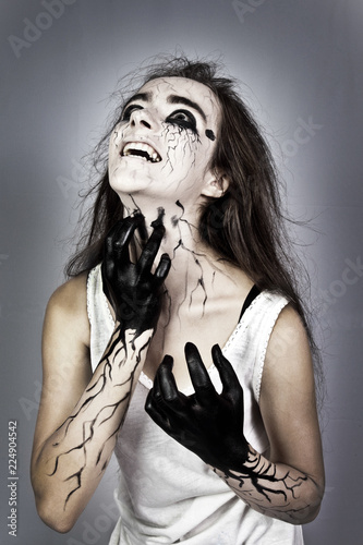 Portrait screaming mad girl with black veins on her face clawing his neck. concept of halloween and day of the dead. halloween makeup photo